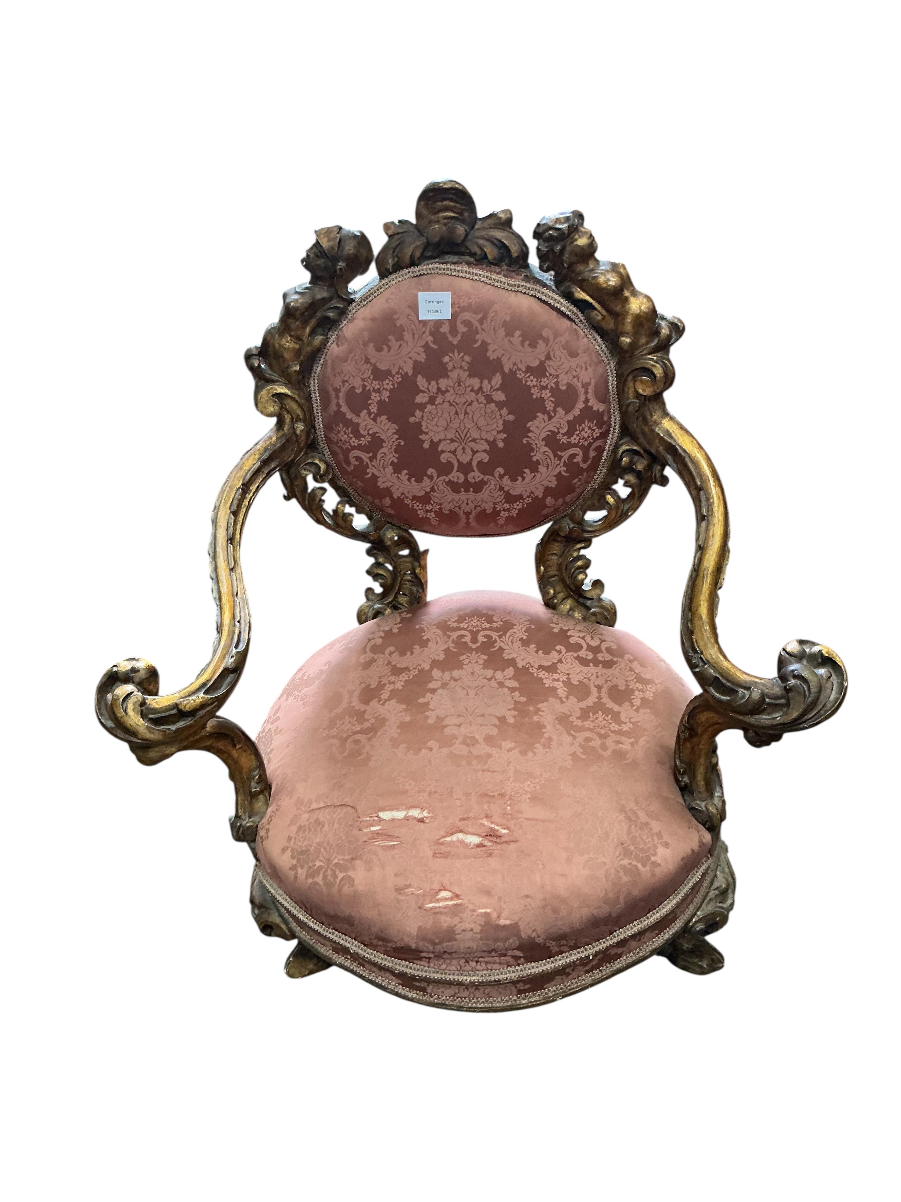 A 19th century Italian parcel gilt baroque revival armchair decorated with caryatids and leaf scrolls, upholstered in pink damask, fabric torn, width 80cm, depth 60cm, height 90cm